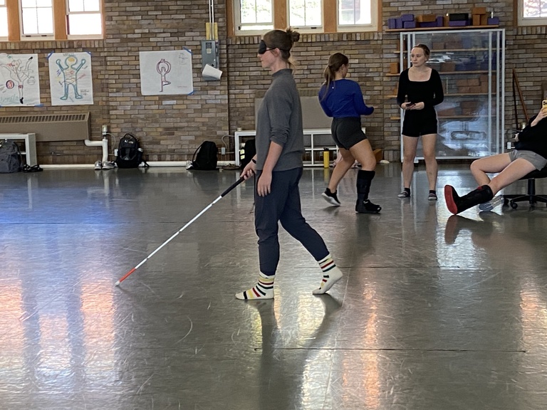 Assistant director and MFA candidate Sophia McLaughlin wears a blindfold and holds a white cane as she walks through the Halsey Hall gym during workshop with Extended Learning education coordinator Crystal Beighley.