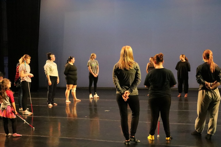 UI Dance Company dancers and students from Extended Learning Program (Iowa Educational Services for the Blind and Visually Impaired) circle up on the Space Place stage at the beginning of workshop