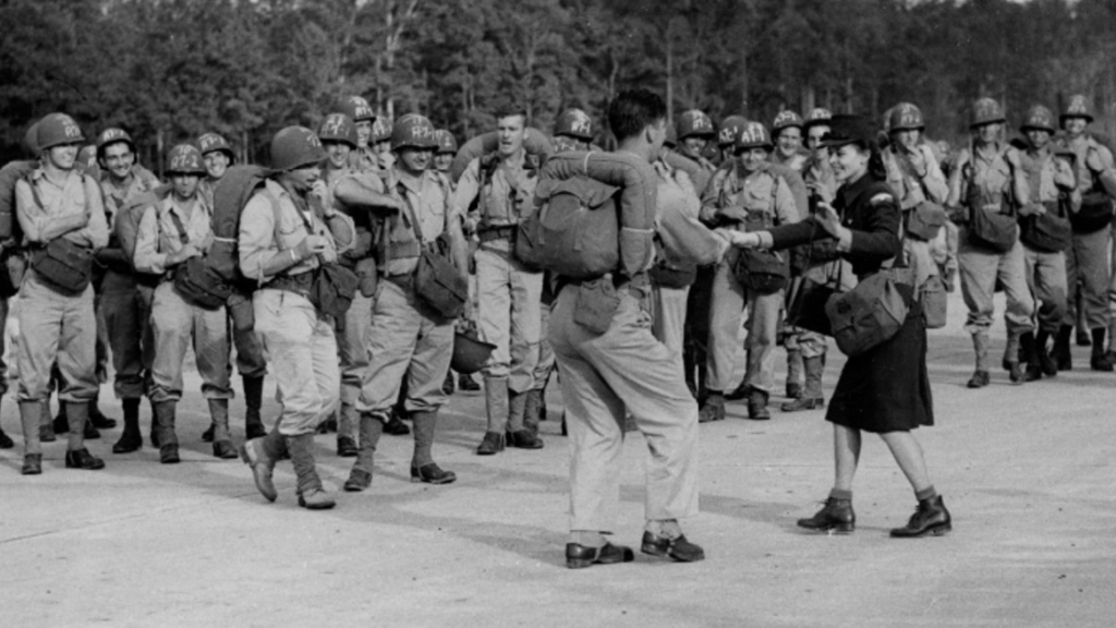 soldiers standing watching two people dance the jitterbug