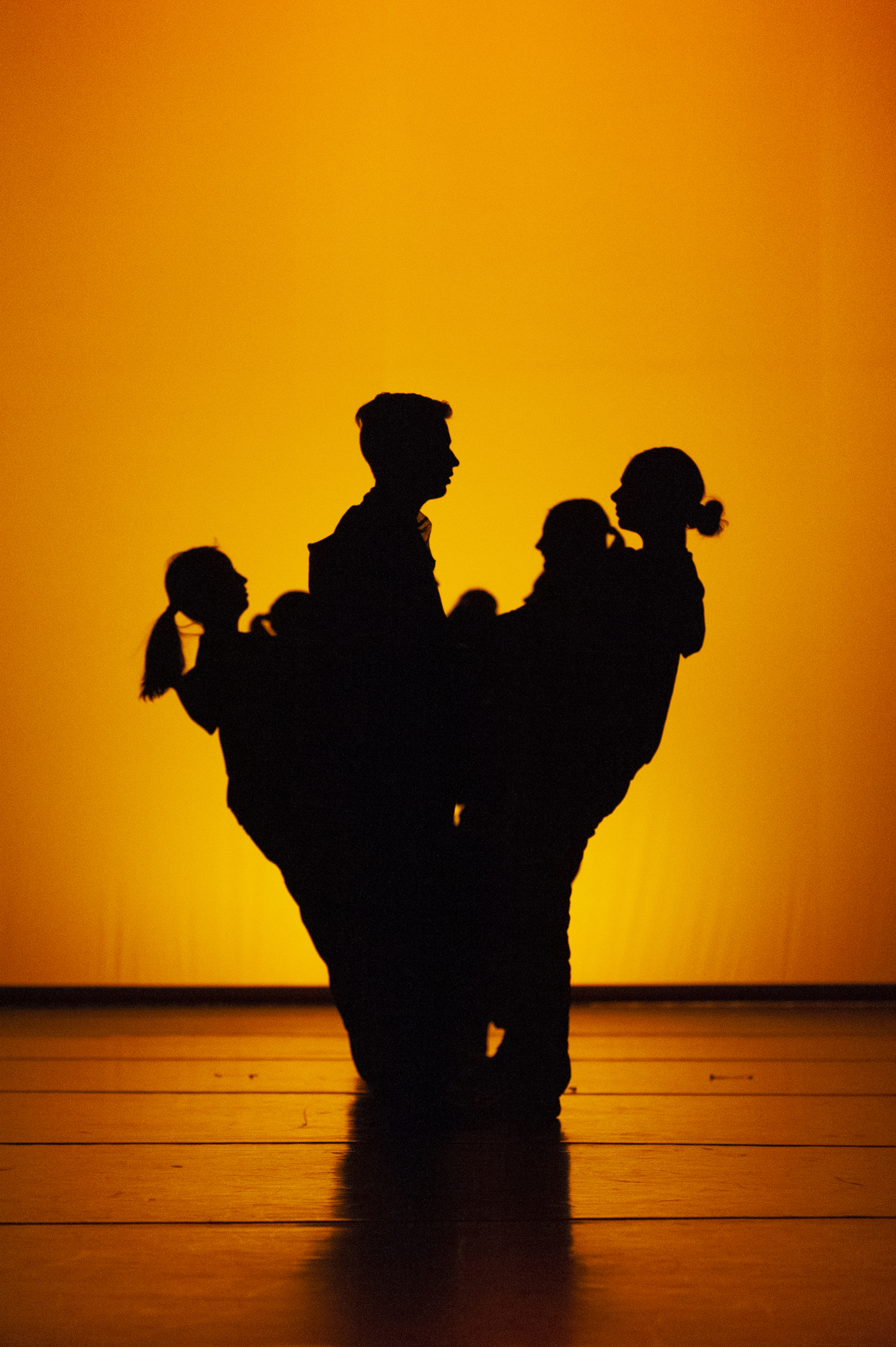 dance grad students on stage silhouetted against a gold-lit backdrop