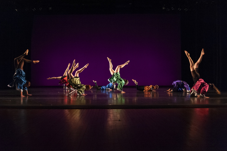 students performing with hands on floor and feet in the air during a MFA thesis performance in 2023