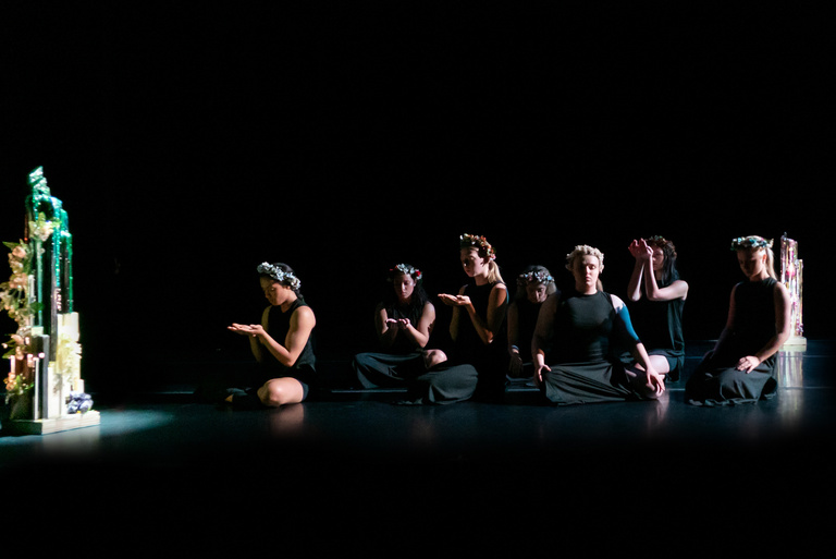 a group of dancers on a darkened stage with soft lighting