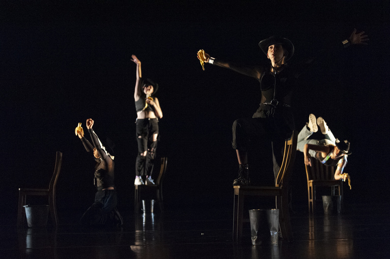 a group of dimly lit dancers on a darkened stage