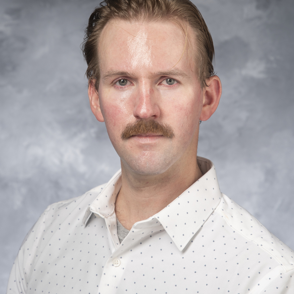 Photo of Colin DeJong from shoulders up, facing forward, white shirt, blond hair with mustache