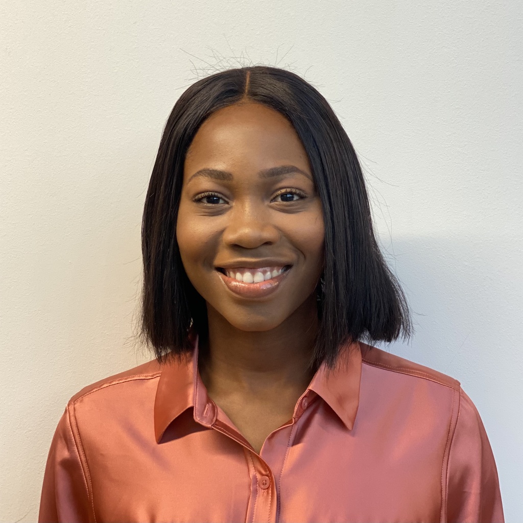 Headshot of Gloria Sitso Ahlijah, facing forward. She is smiling, wearing a pink button-down shirt