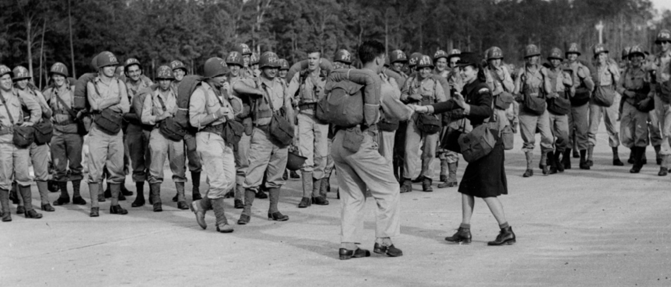 soldiers standing watching two people dance the jitterbug