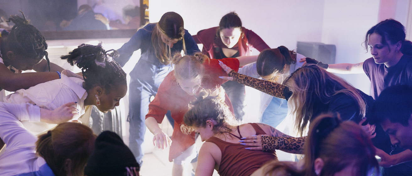 group of dancers performing in a house setting, with bright colorful lights and street clothing