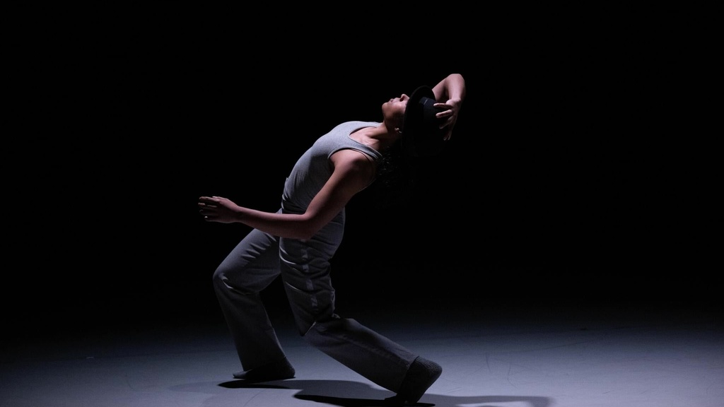 student dancer Soraya Cohen leaning backward and illuminated by a spotlight